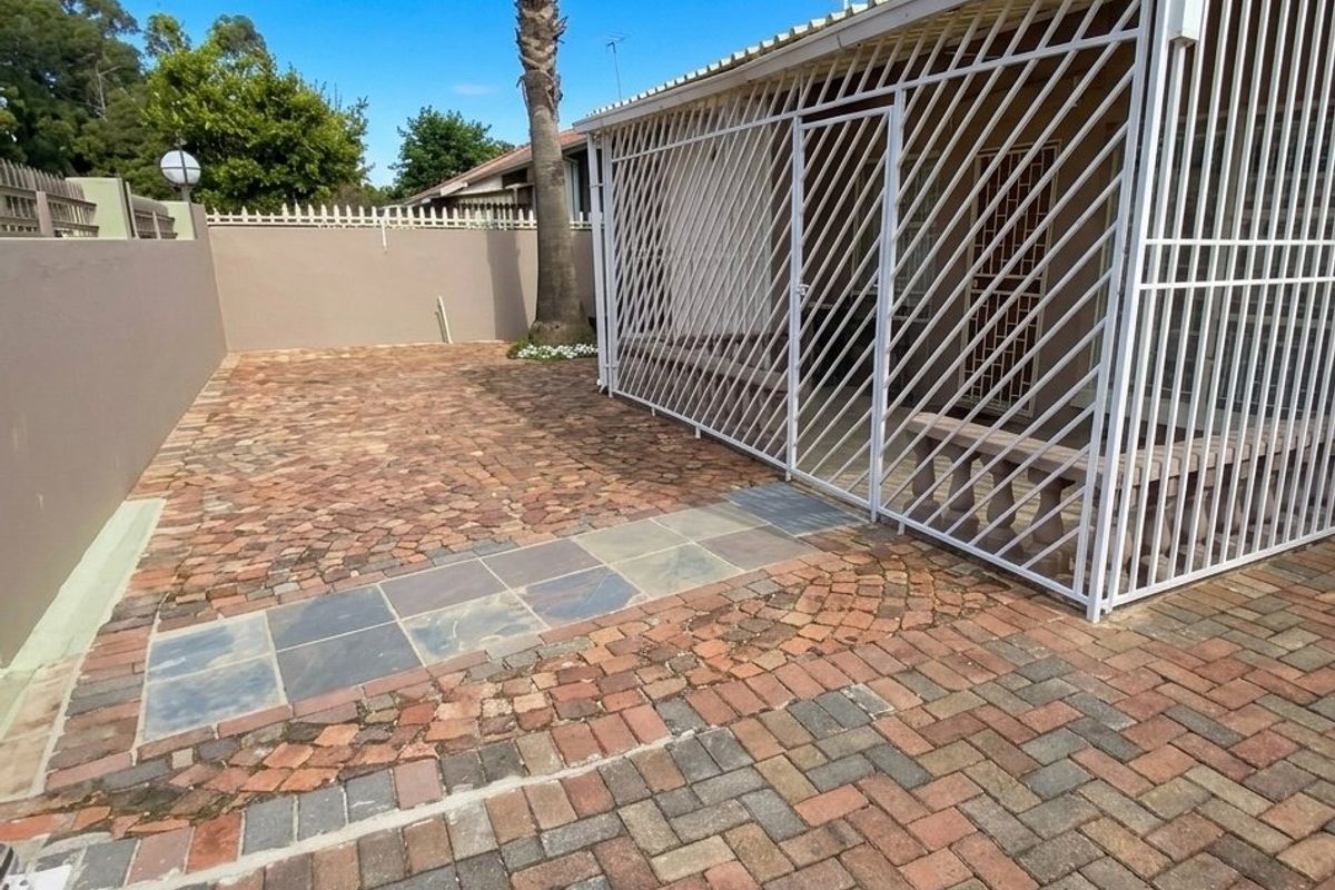 A private rear courtyard featuring paved flooring, a secure gated patio area, and perimeter walling.