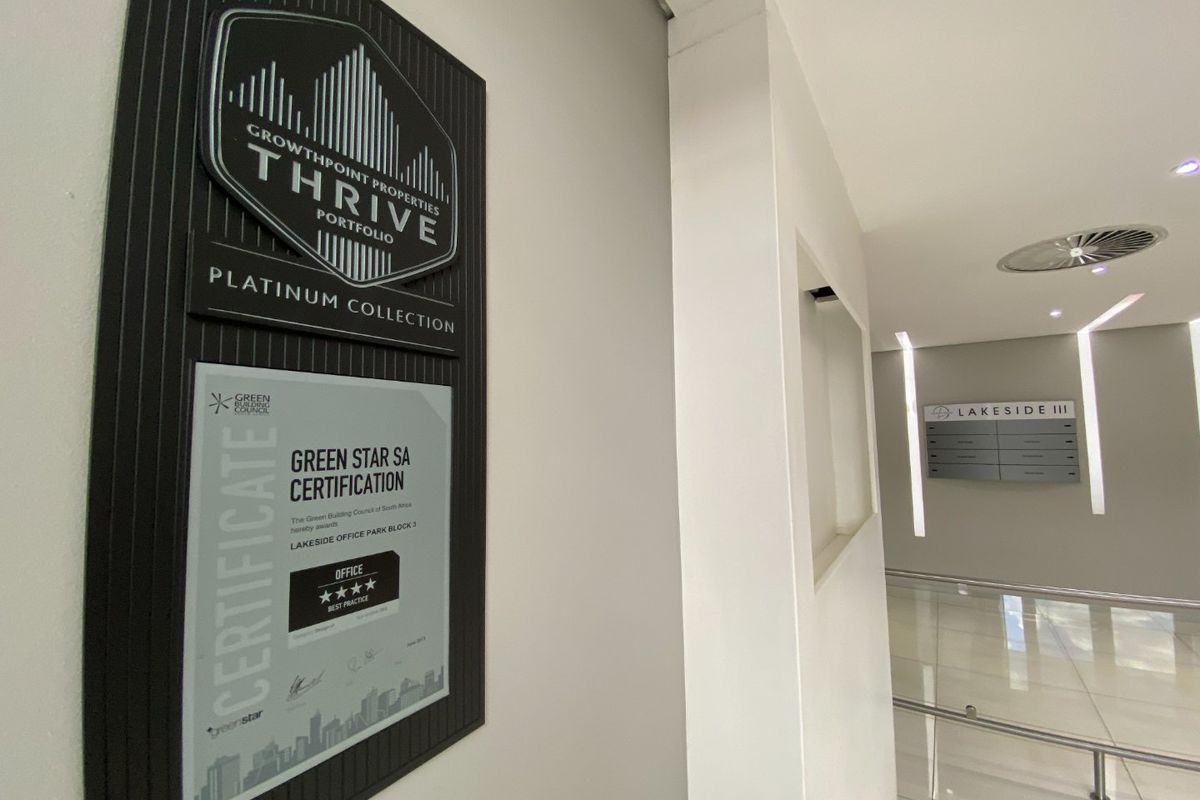 Modern commercial building entrance lobby featuring professional signage, Green Star certification plaque, and clean, well-maintained tiled flooring and recessed lighting.