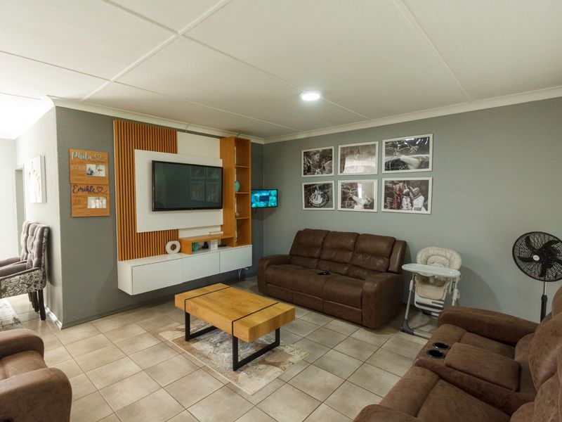 A comfortable living room featuring tiled flooring and a modern built-in media wall unit with integrated shelving.