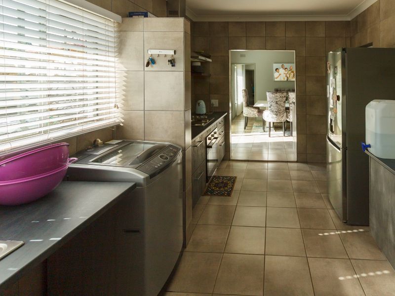 A functional kitchen featuring tiled walls and flooring, built-in cabinetry, and a dedicated space for laundry appliances.