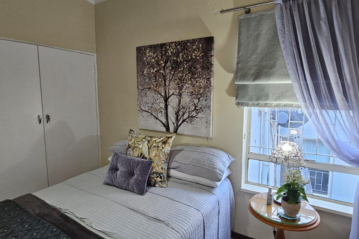 A cozy bedroom featuring a built-in wardrobe and a window with natural light, providing a functional and comfortable living space.