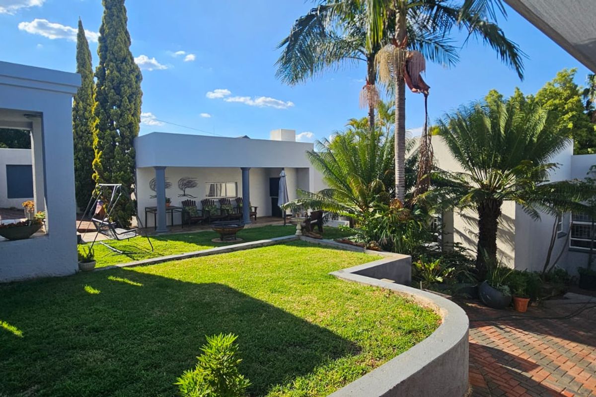 A well-maintained rear garden featuring a manicured lawn, a covered patio area, and brick paving, providing a pleasant outdoor living space.