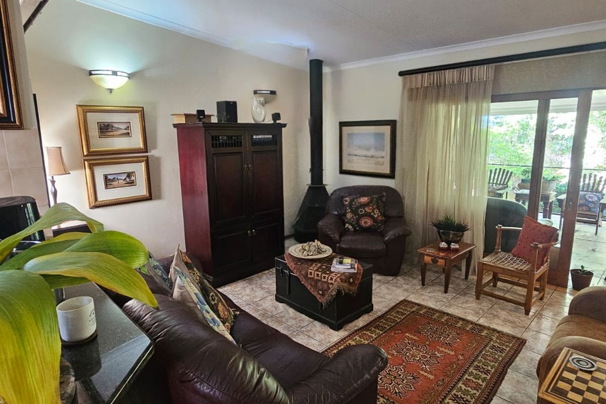 A comfortable living room featuring tiled flooring, a freestanding fireplace, and large sliding glass doors that provide access to an outdoor patio area.