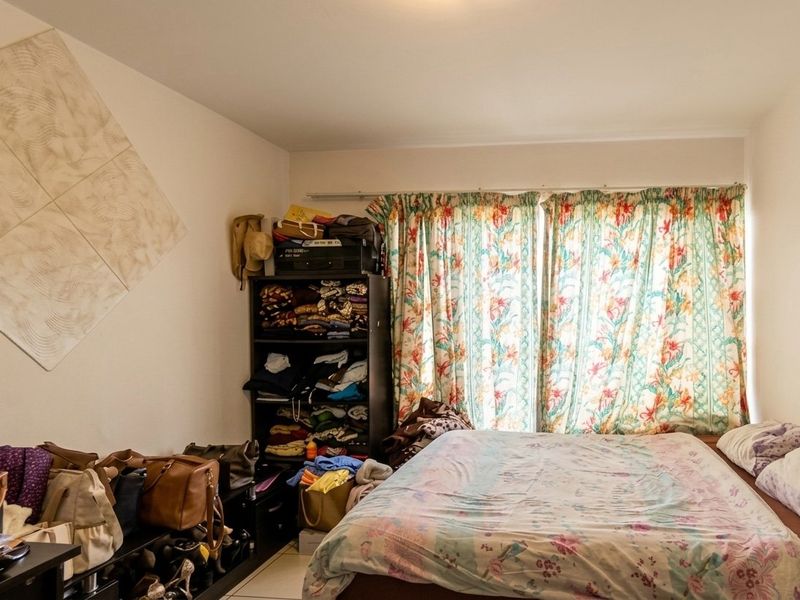 A bedroom featuring tiled flooring and window curtain tracks, offering a functional space ready for personalization and updates.