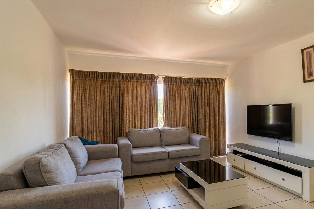 A comfortable living room featuring neutral tiled flooring and a central ceiling light fixture, providing a functional and well-maintained space.