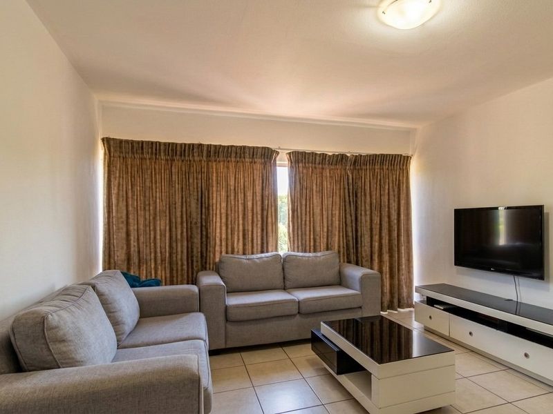 A comfortable living room featuring neutral tiled flooring and a central ceiling light fixture, providing a functional and well-maintained space.