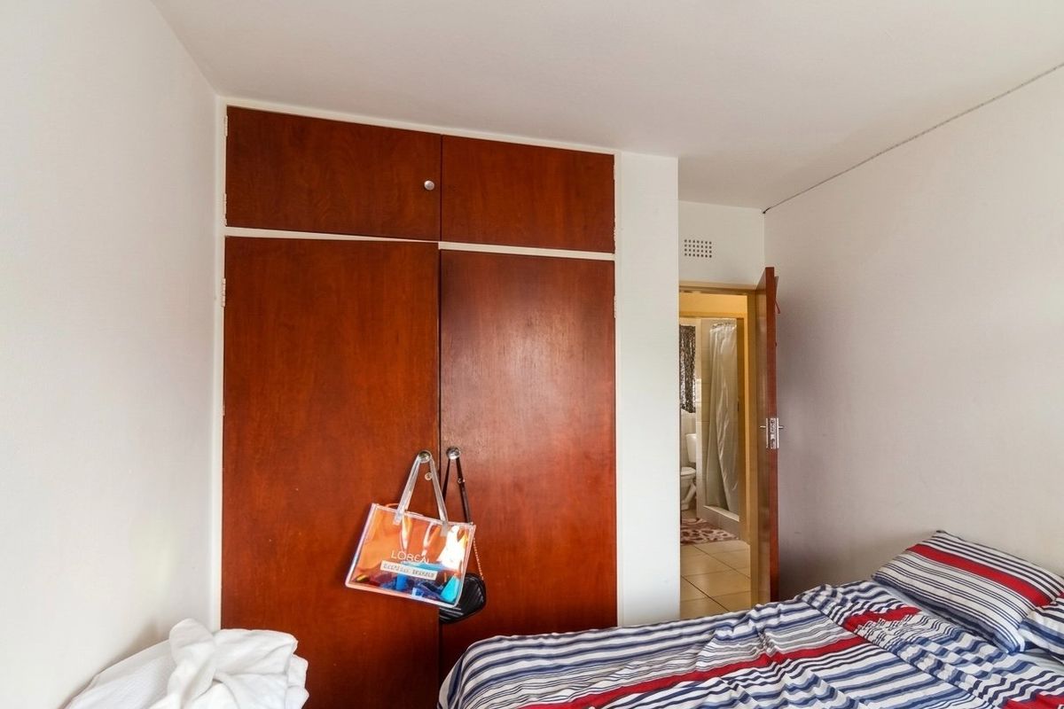 A bedroom featuring a full-height built-in wooden wardrobe and direct access to an adjoining bathroom.