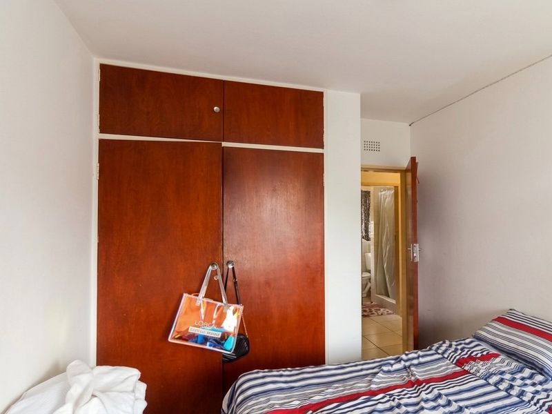 A bedroom featuring a full-height built-in wooden wardrobe and direct access to an adjoining bathroom.