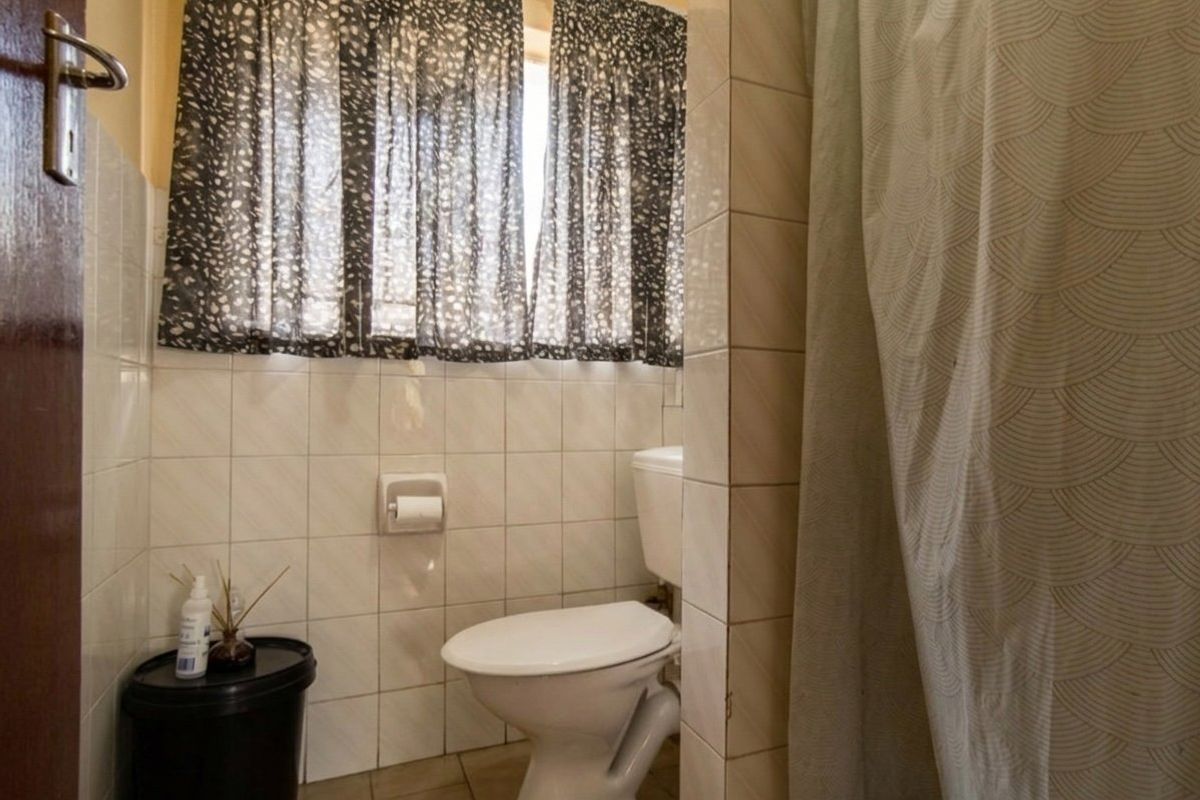 A functional bathroom featuring tiled walls and a standard toilet, offering a practical layout ready for modern updates.