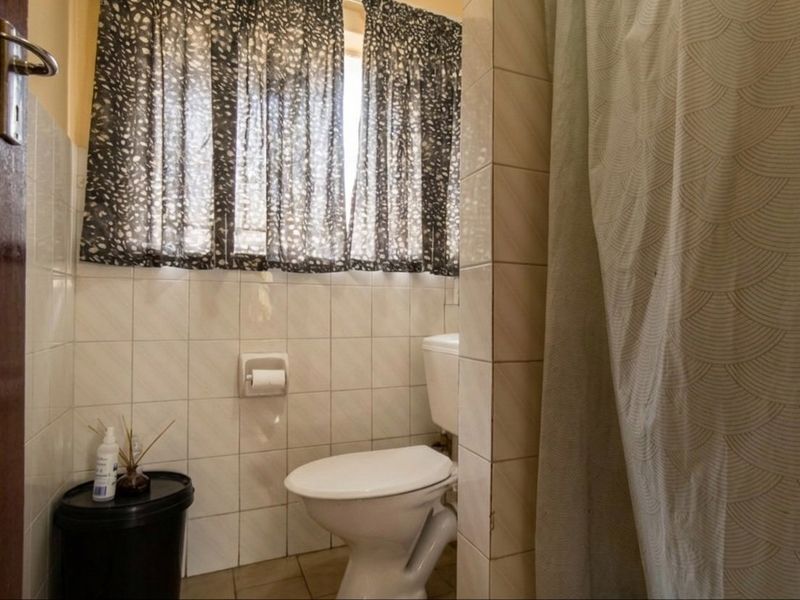 A functional bathroom featuring tiled walls and a standard toilet, offering a practical layout ready for modern updates.