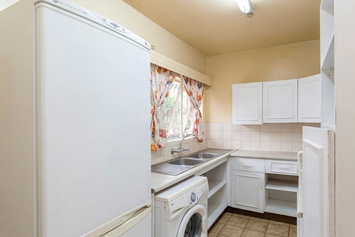 A functional kitchen featuring white cabinetry, double basin sink, tiled splashback, and tiled flooring, offering a practical layout for daily use.