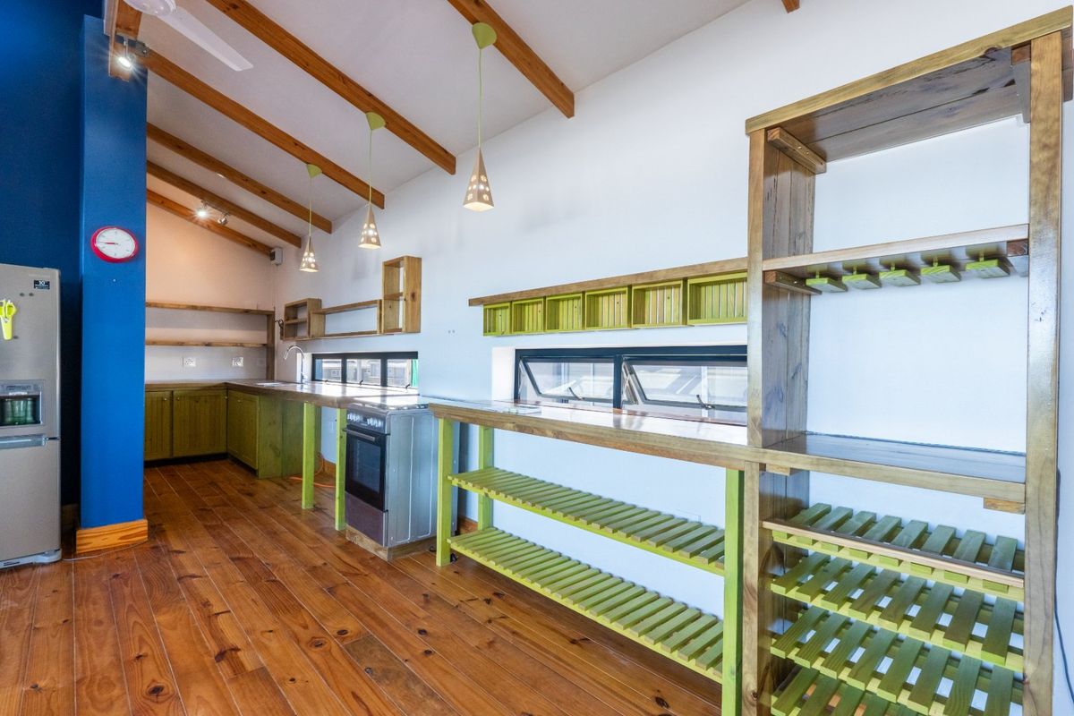A rustic-style kitchen featuring exposed timber ceiling beams, hardwood flooring, custom timber shelving, and a freestanding oven with ample prep space.