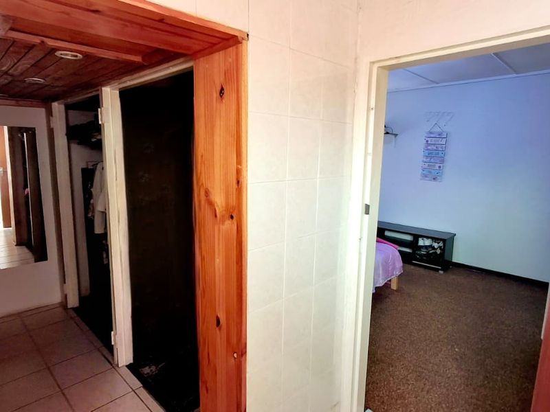 A functional hallway featuring tiled flooring and timber ceiling accents, providing access to adjacent rooms within the property.