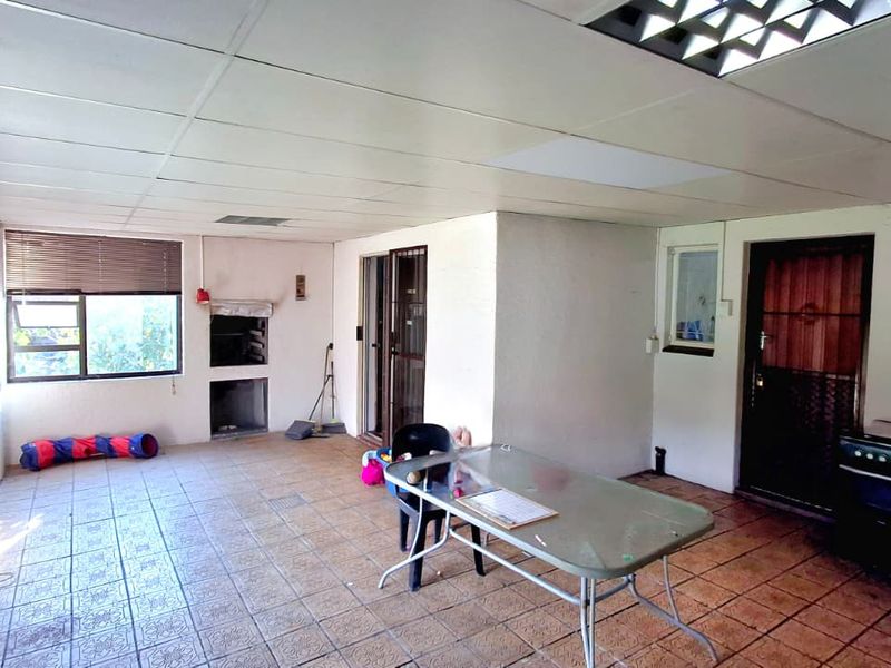 Covered patio area featuring a built-in braai, tiled flooring, and direct access to the home through sliding doors.