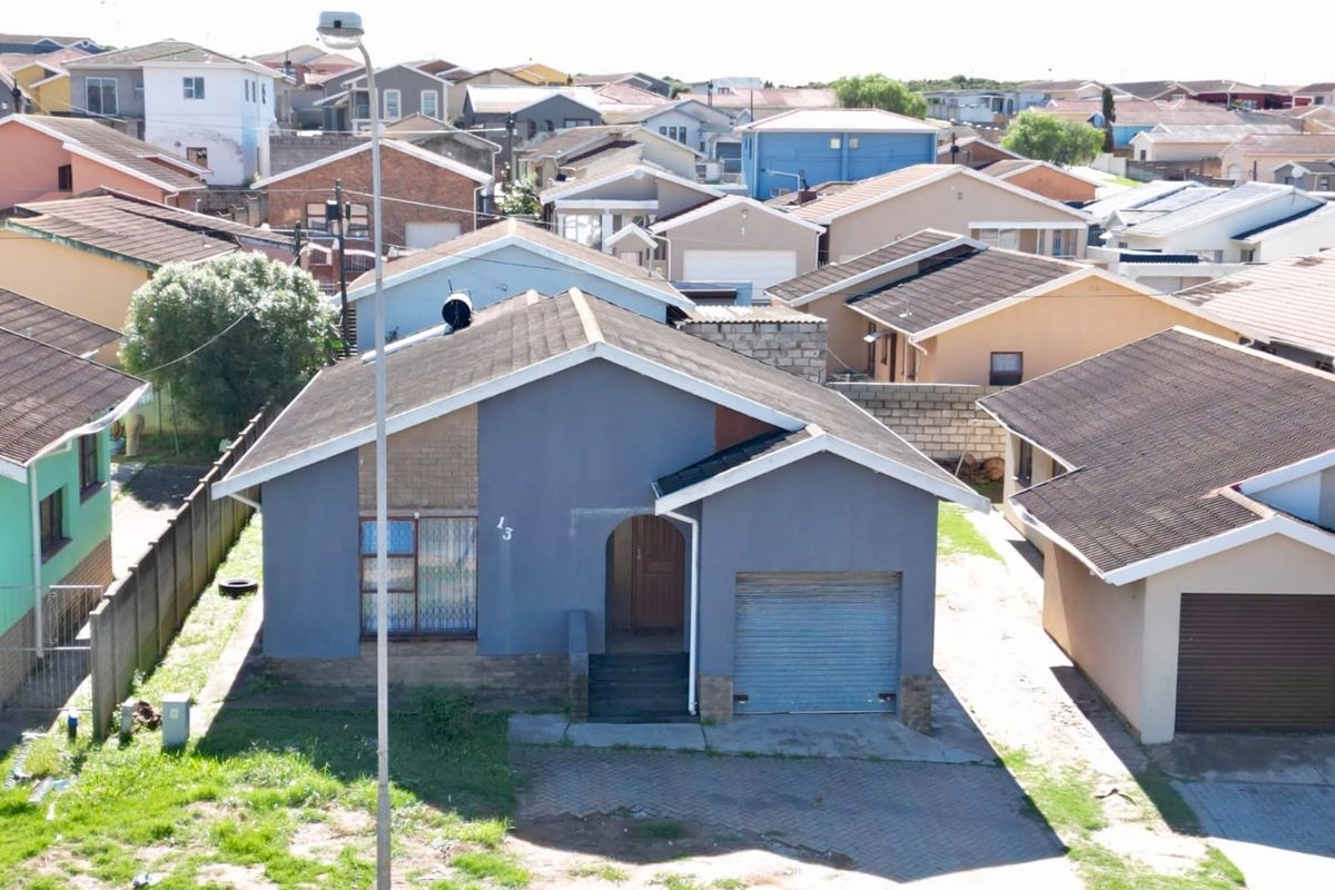 An elevated view of a detached single-story house featuring a tiled roof, integrated garage, and paved driveway in a residential neighborhood.