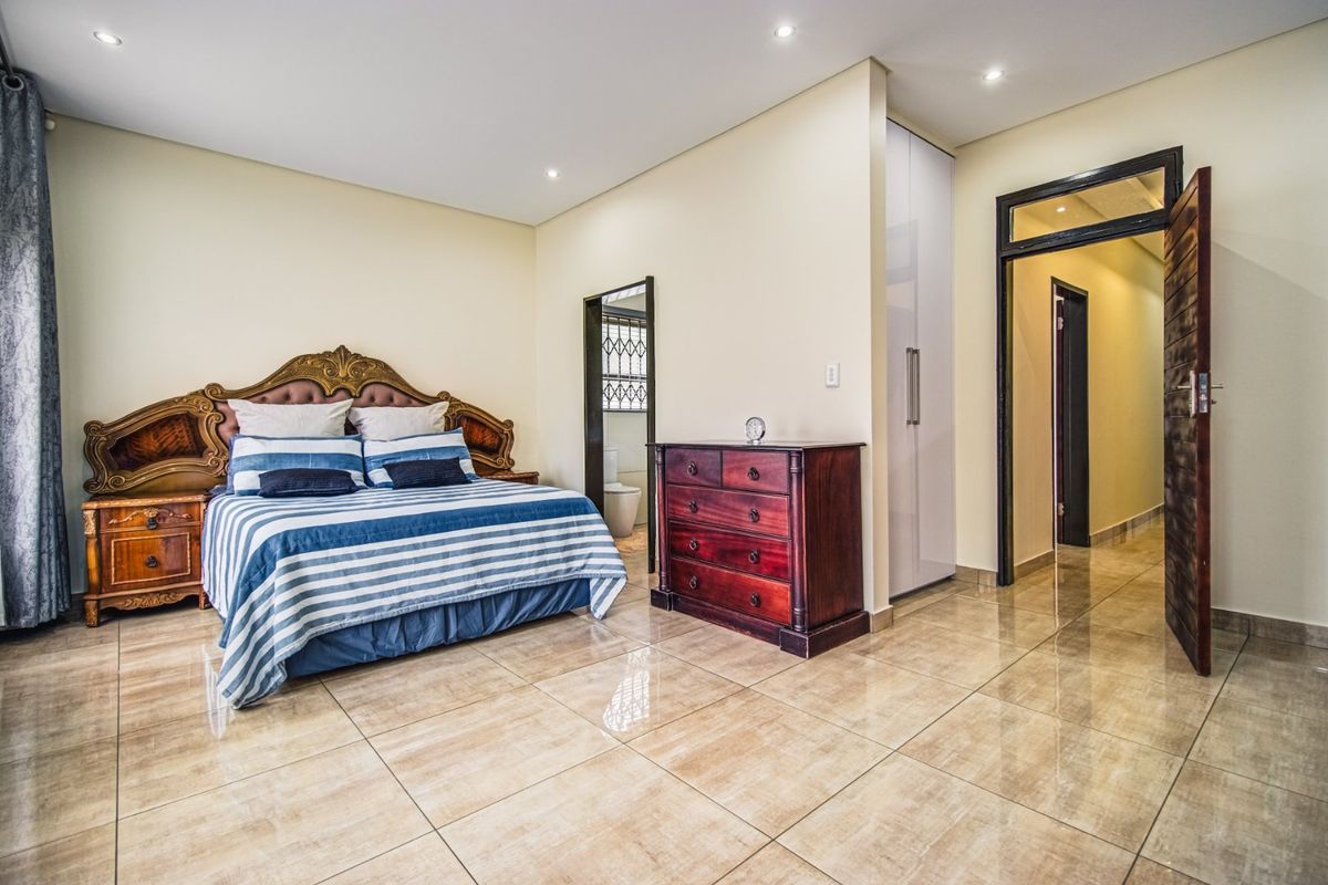 Spacious bedroom featuring polished tiled flooring, recessed downlighting, and built-in cupboard storage with direct access to an en-suite bathroom.