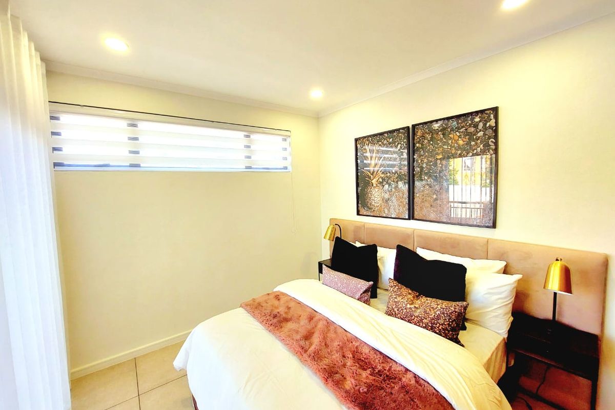 A well-maintained bedroom featuring tiled flooring, recessed downlighting, and a modern horizontal window blind.