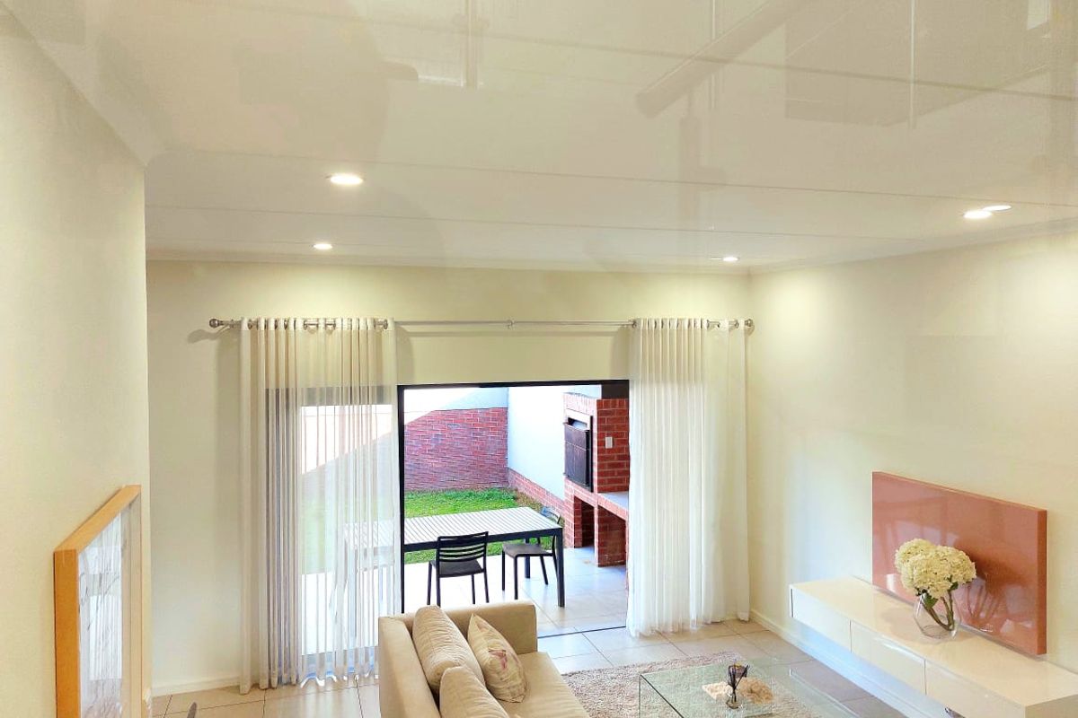Bright and modern living room featuring tiled floors, recessed lighting, and seamless access to an outdoor patio area through large sliding glass doors.