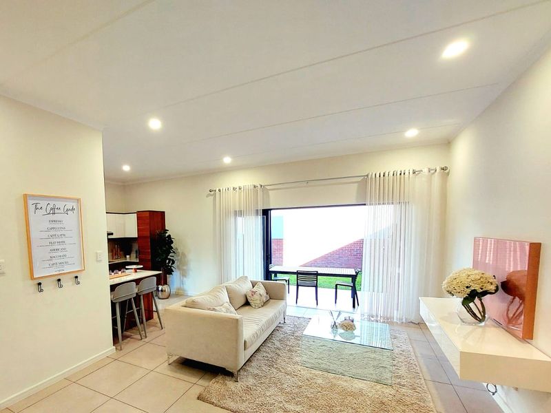 Bright open-plan living area featuring tiled floors, recessed lighting, and seamless flow to an outdoor patio through large sliding glass doors.