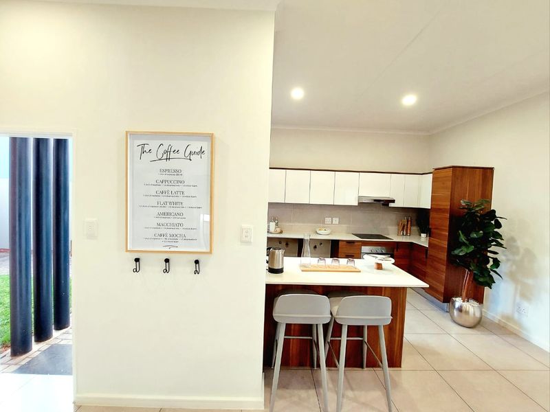 Modern kitchen featuring sleek wood-finish cabinetry, white stone countertops, integrated appliances, and a functional breakfast island, creating a clean and contemporary culinary space.