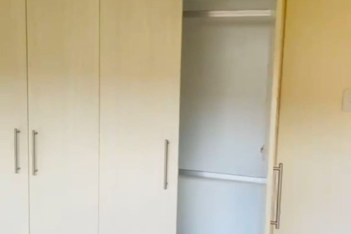A bedroom featuring a built-in wardrobe with light wood-finish doors and internal shelving.