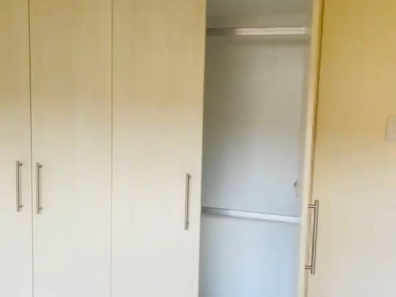 A bedroom featuring a built-in wardrobe with light wood-finish doors and internal shelving.