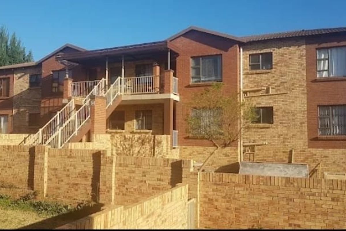 Rear view of a multi-story townhouse complex featuring face brick construction, an external staircase, and private balcony access.