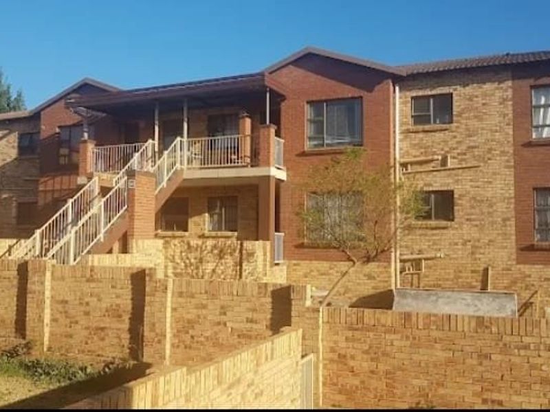 Rear view of a multi-story townhouse complex featuring face brick construction, an external staircase, and private balcony access.