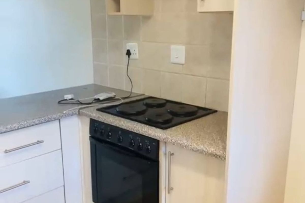 Compact kitchen featuring built-in cabinetry, laminate countertops, and a built-in electric oven and hob with tiled backsplash.