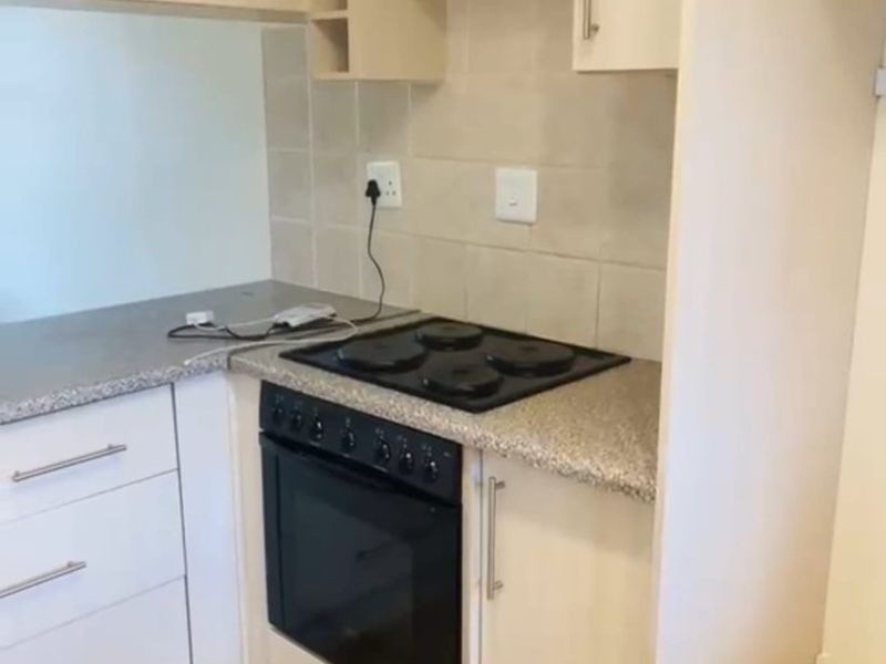 Compact kitchen featuring built-in cabinetry, laminate countertops, and a built-in electric oven and hob with tiled backsplash.