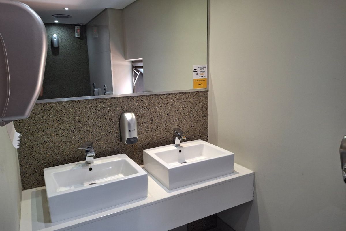Modern commercial bathroom featuring a double vanity with vessel sinks, chrome faucets, and a large wall-mounted mirror.