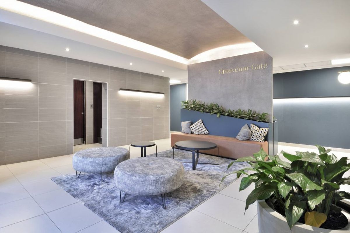 Modern commercial building lobby featuring tiled floors, recessed cove lighting, and a contemporary feature wall with integrated bench seating.