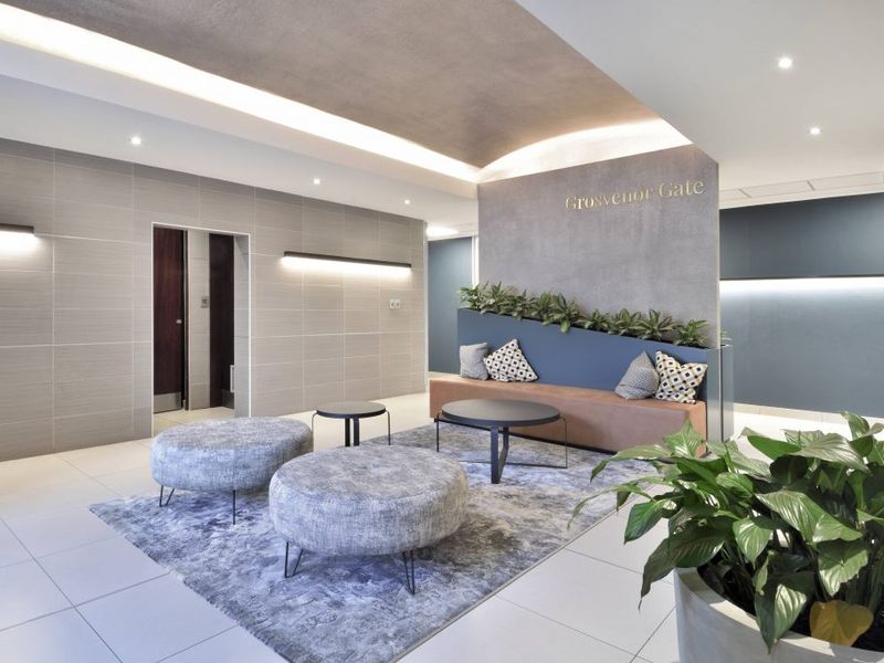 Modern commercial building lobby featuring tiled floors, recessed cove lighting, and a contemporary feature wall with integrated bench seating.