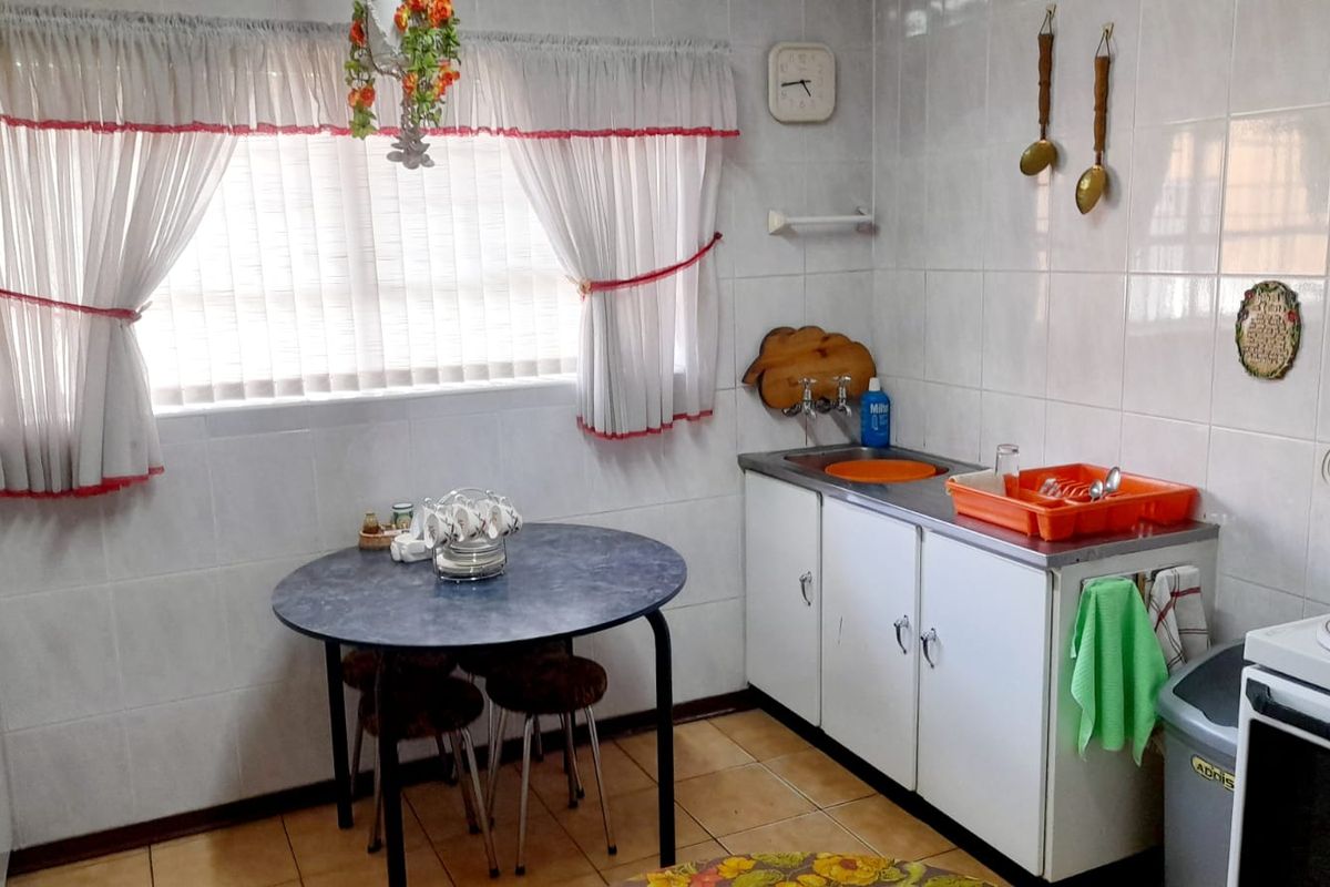 A functional kitchen featuring tiled walls, tiled flooring, stainless steel sink, and built-in cabinetry, offering a dated aesthetic ready for modernization.