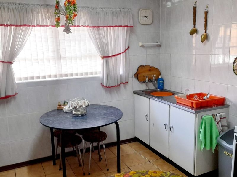 A functional kitchen featuring tiled walls, tiled flooring, stainless steel sink, and built-in cabinetry, offering a dated aesthetic ready for modernization.