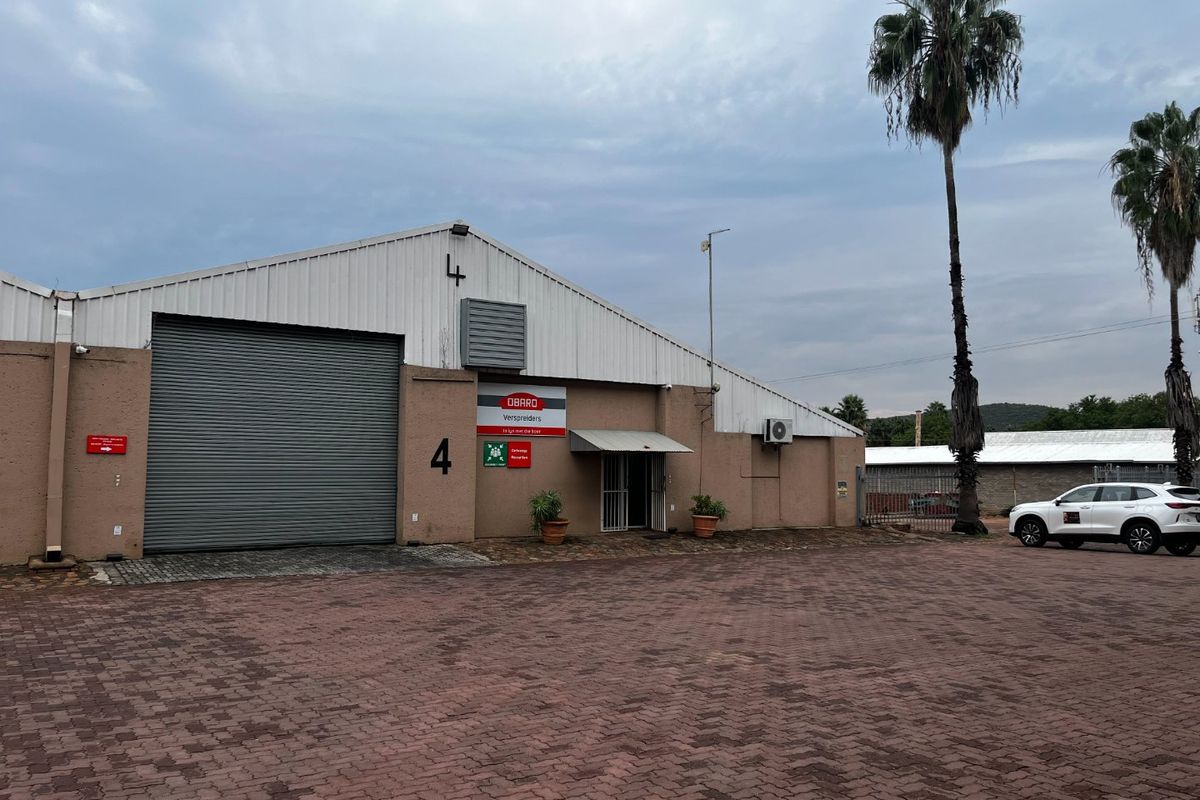 Commercial warehouse unit featuring a large roller shutter door, paved exterior area, and metal roofing, suitable for industrial or storage operations.