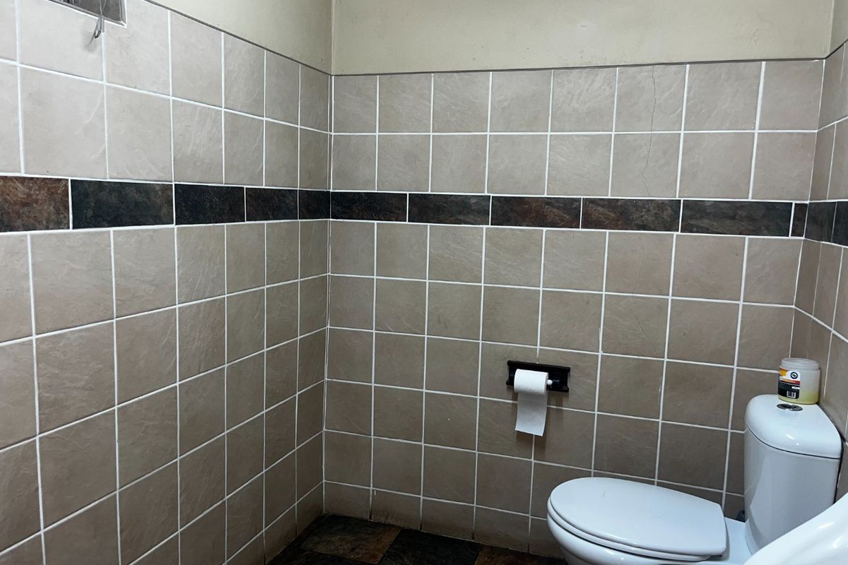 A small bathroom featuring tiled walls with a decorative border and tiled flooring, equipped with a standard toilet.