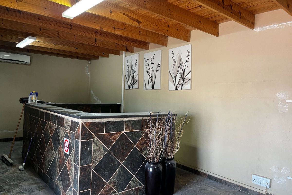 A commercial reception area featuring a tiled service counter, exposed timber beam ceiling, and wall-mounted air conditioning unit.