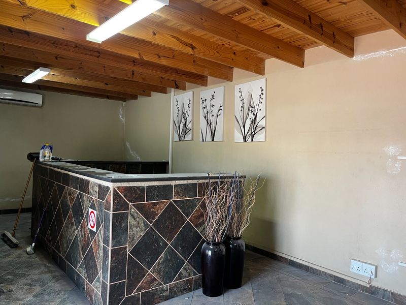 A commercial reception area featuring a tiled service counter, exposed timber beam ceiling, and wall-mounted air conditioning unit.