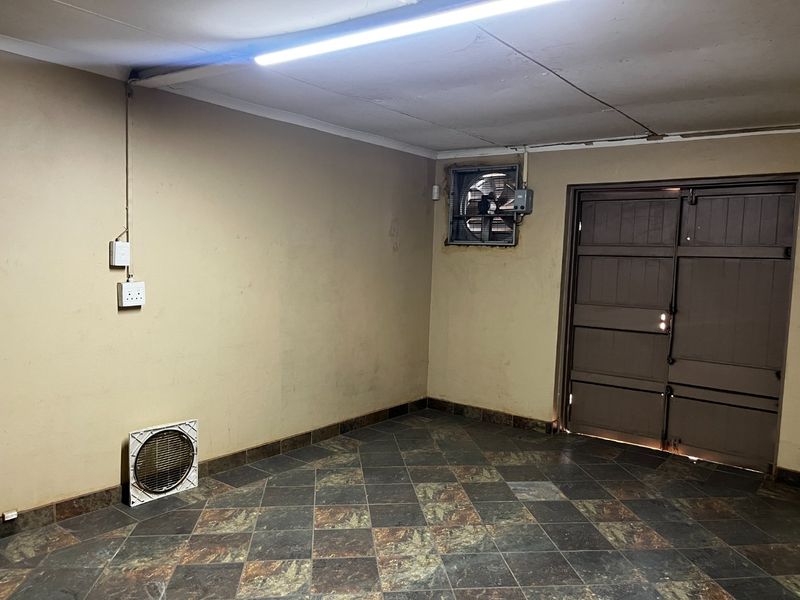 A functional, empty garage space featuring tiled flooring, built-in ventilation fans, and direct access through a heavy-duty door.