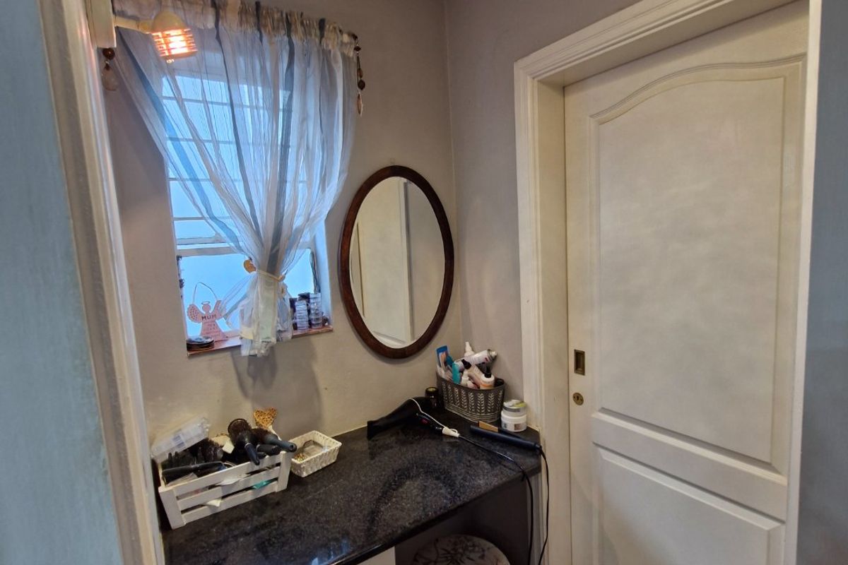 A compact bedroom vanity area featuring a granite countertop, built-in cabinetry, and tiled flooring, providing a functional space for personal grooming.