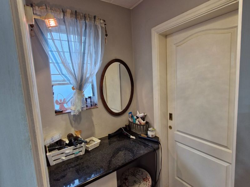 A compact bedroom vanity area featuring a granite countertop, built-in cabinetry, and tiled flooring, providing a functional space for personal grooming.