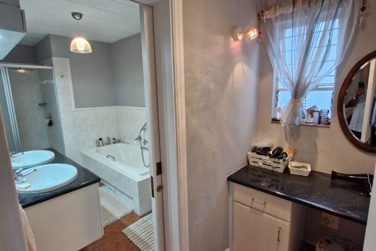 A functional bathroom featuring a dual vanity with granite countertops, a separate bathtub, and a shower enclosure with tiled flooring throughout.