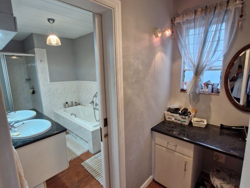 A functional bathroom featuring a dual vanity with granite countertops, a separate bathtub, and a shower enclosure with tiled flooring throughout.