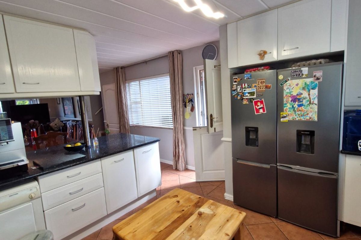 A functional kitchen featuring white cabinetry, granite countertops, and tiled flooring, with a unique dutch door leading to the exterior.