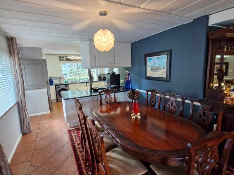 Open plan dining and kitchen area featuring tiled flooring, dark accent wall, and functional kitchen cabinetry with granite countertops.
