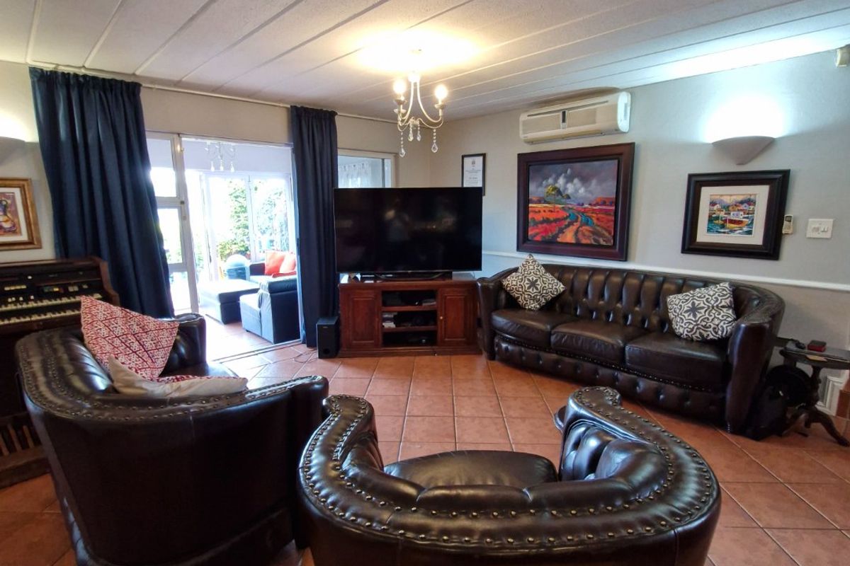 Spacious living room featuring terracotta tiled flooring, a split-system air conditioner, and direct access to an outdoor patio area through sliding glass doors.