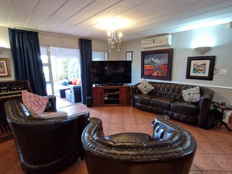 Spacious living room featuring terracotta tiled flooring, a split-system air conditioner, and direct access to an outdoor patio area through sliding glass doors.