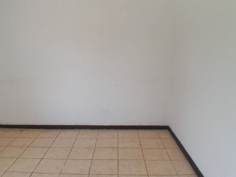 An empty bedroom featuring tiled flooring and plain walls, providing a blank canvas for renovation or interior design updates.