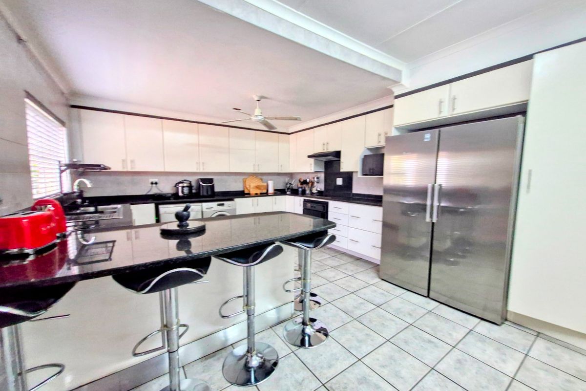 Spacious kitchen featuring granite countertops, ample cabinetry, a breakfast bar, and tiled flooring, designed for functional daily use.